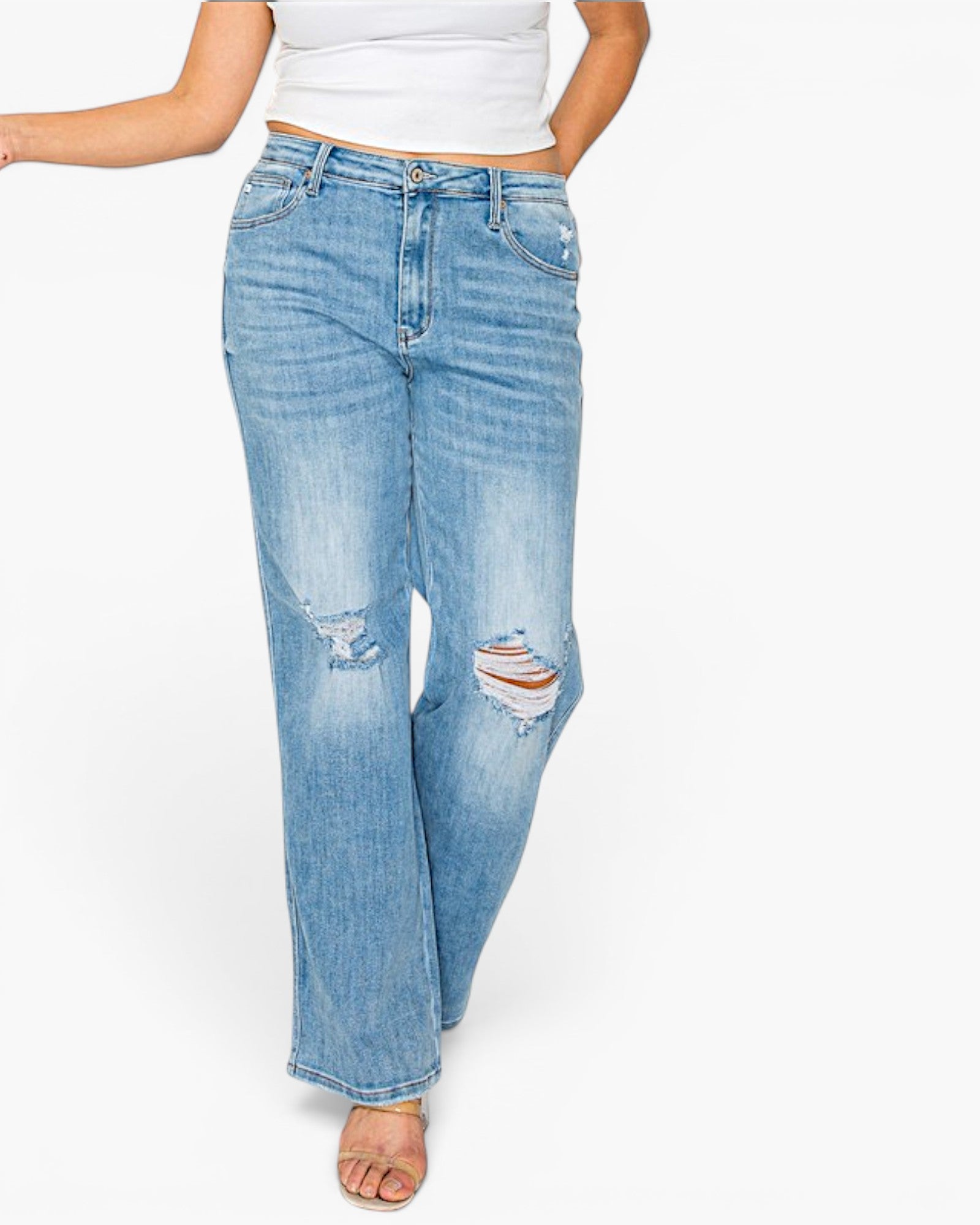 A person wearing light-wash blue distressed jeans with a wide leg fit, paired with a white cropped tank top and flat sandals, shown from the waist down against a plain white background.