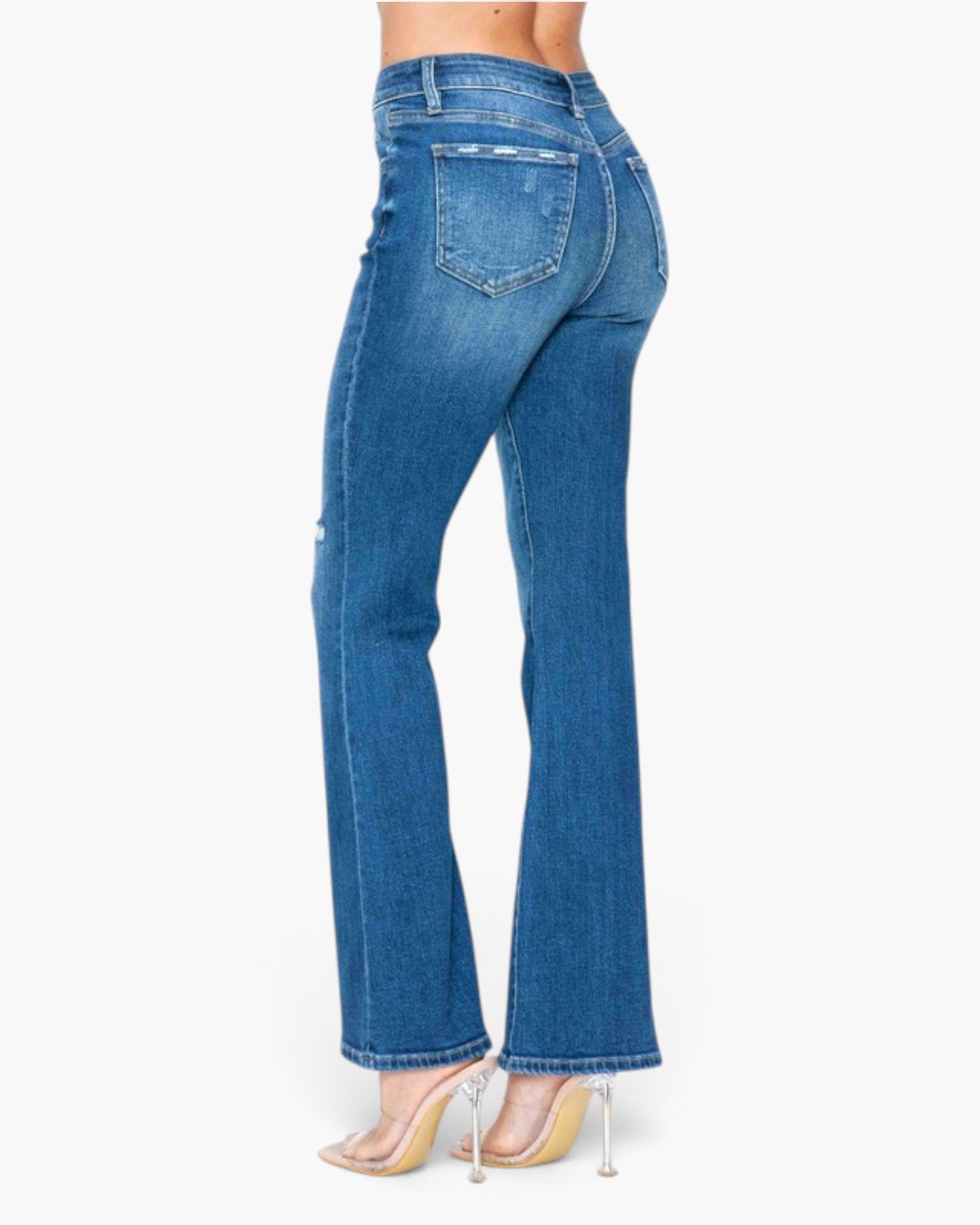 A model shown from the back wearing blue high-waisted flare jeans and clear high-heeled sandals against a plain white background.