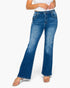 A model wearing a pair of medium-wash blue flare jeans with distressed details on the thighs and knees, paired with a white crop top and clear high-heeled sandals, set against a plain white background.