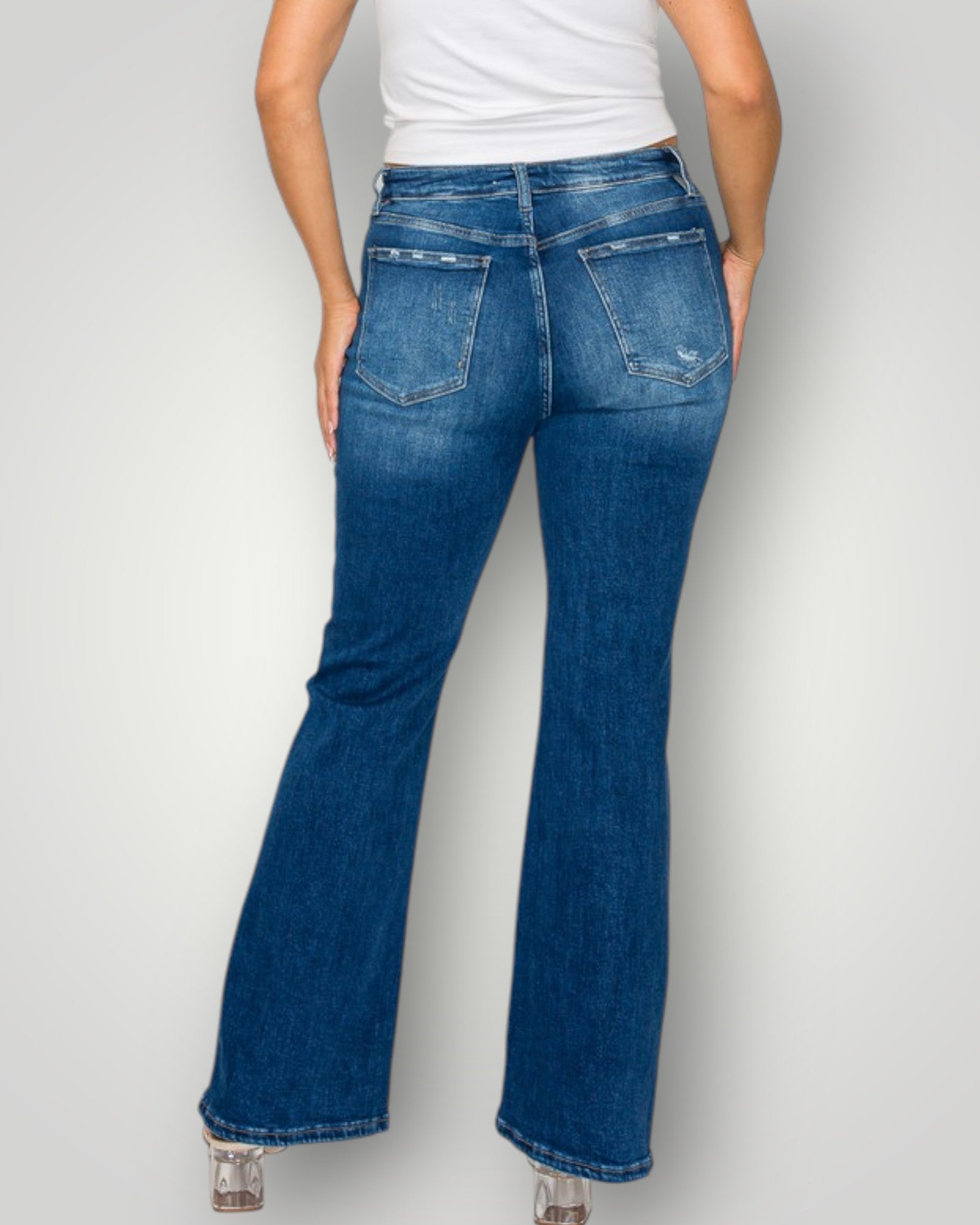 Person wearing blue flared jeans on a plain background