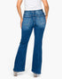 Rear view of a model wearing blue high-waisted flare jeans with a white top, shown against a plain light gray studio background.