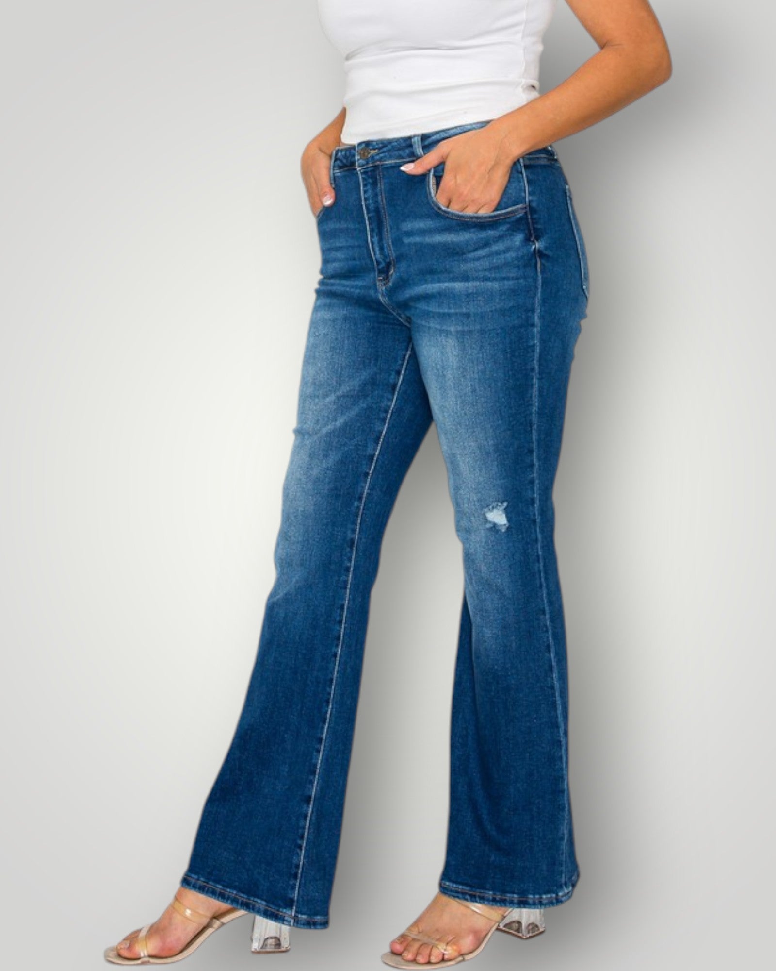 Person wearing blue flared jeans on a plain background