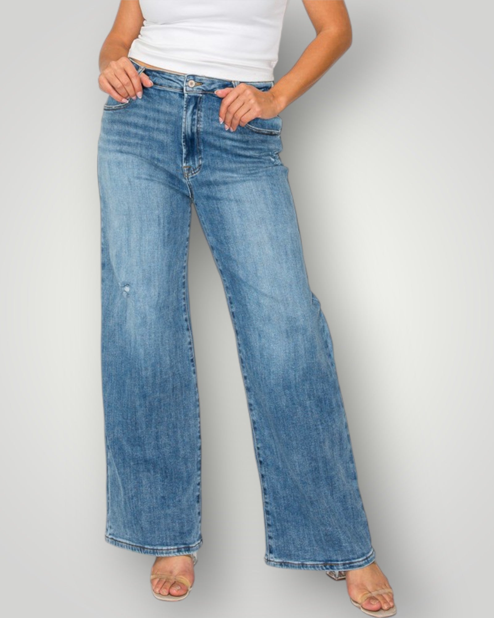 Person wearing light blue jeans on a plain background
