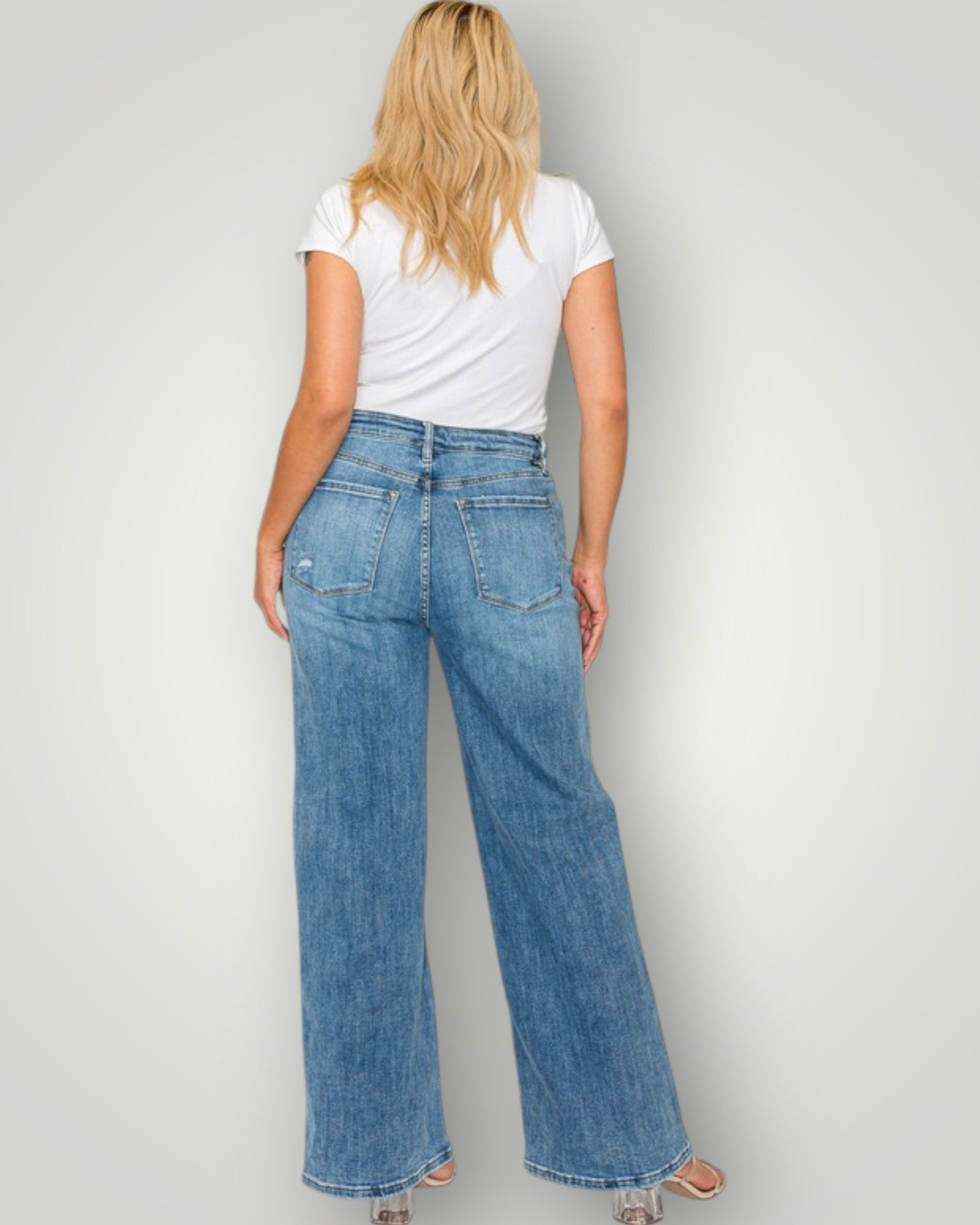 Person wearing blue jeans and a white t-shirt on a plain background