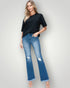 Woman wearing a black top and blue jeans on a plain background
