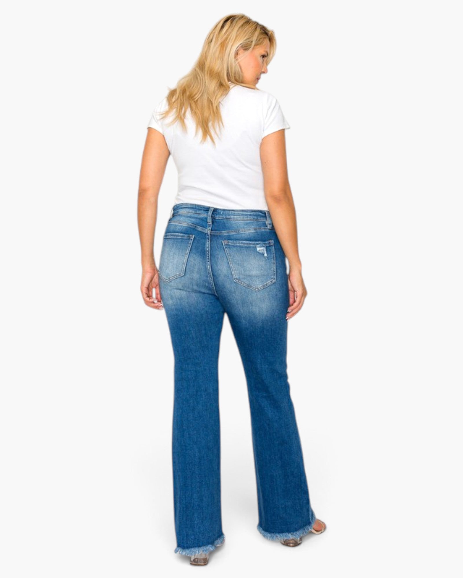 A woman shown from the back wearing blue flare jeans with a white t-shirt, standing against a plain white background.
