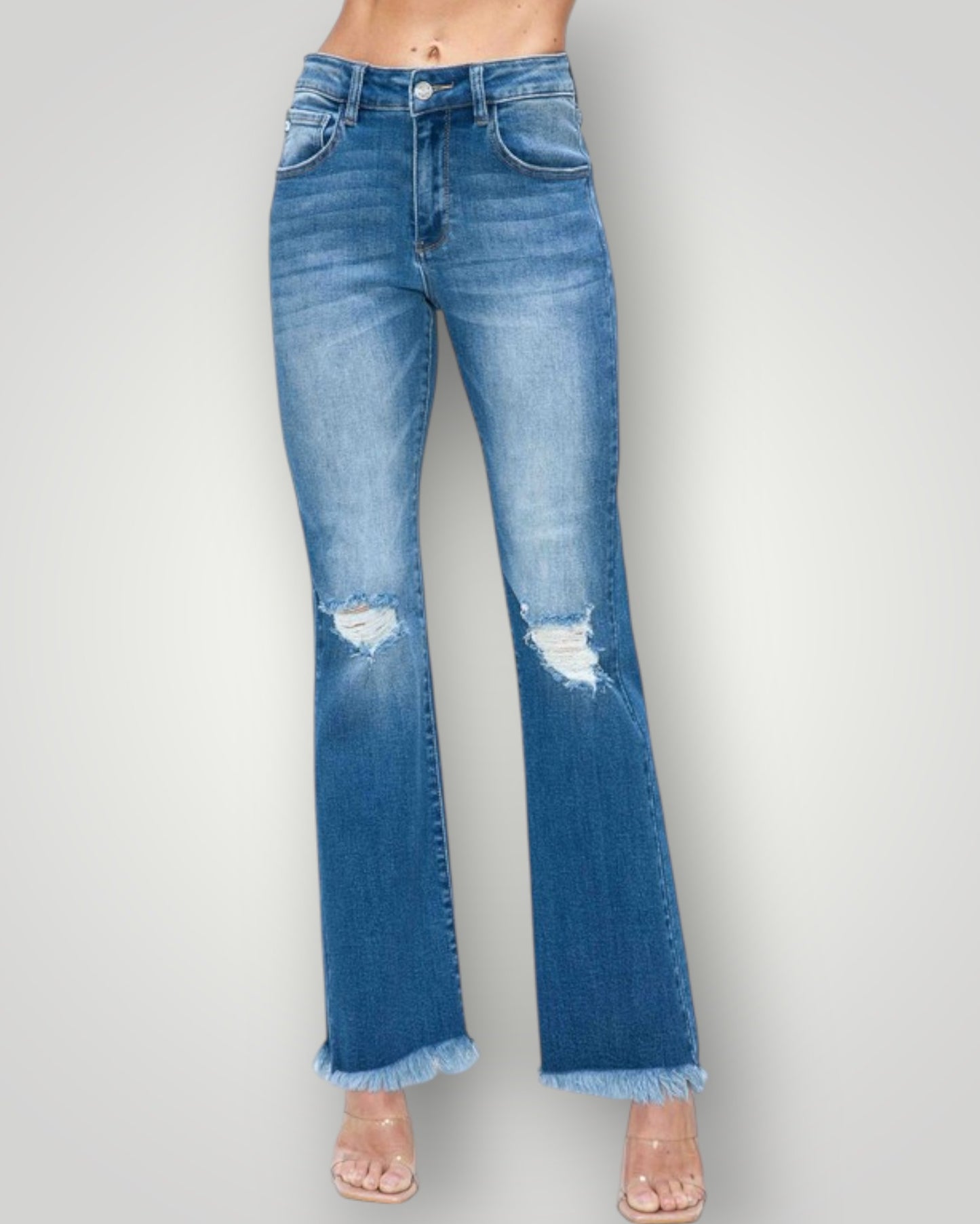 Blue jeans with a frayed hem on a gray background
