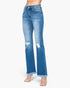A model wearing a pair of medium-wash blue denim flare jeans with distressed rips on the thighs and frayed hems, paired with clear high-heel sandals against a plain white background.