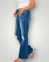 Person wearing blue flared jeans on a plain background