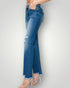 Blue jeans with a distressed look worn by a person on a plain background