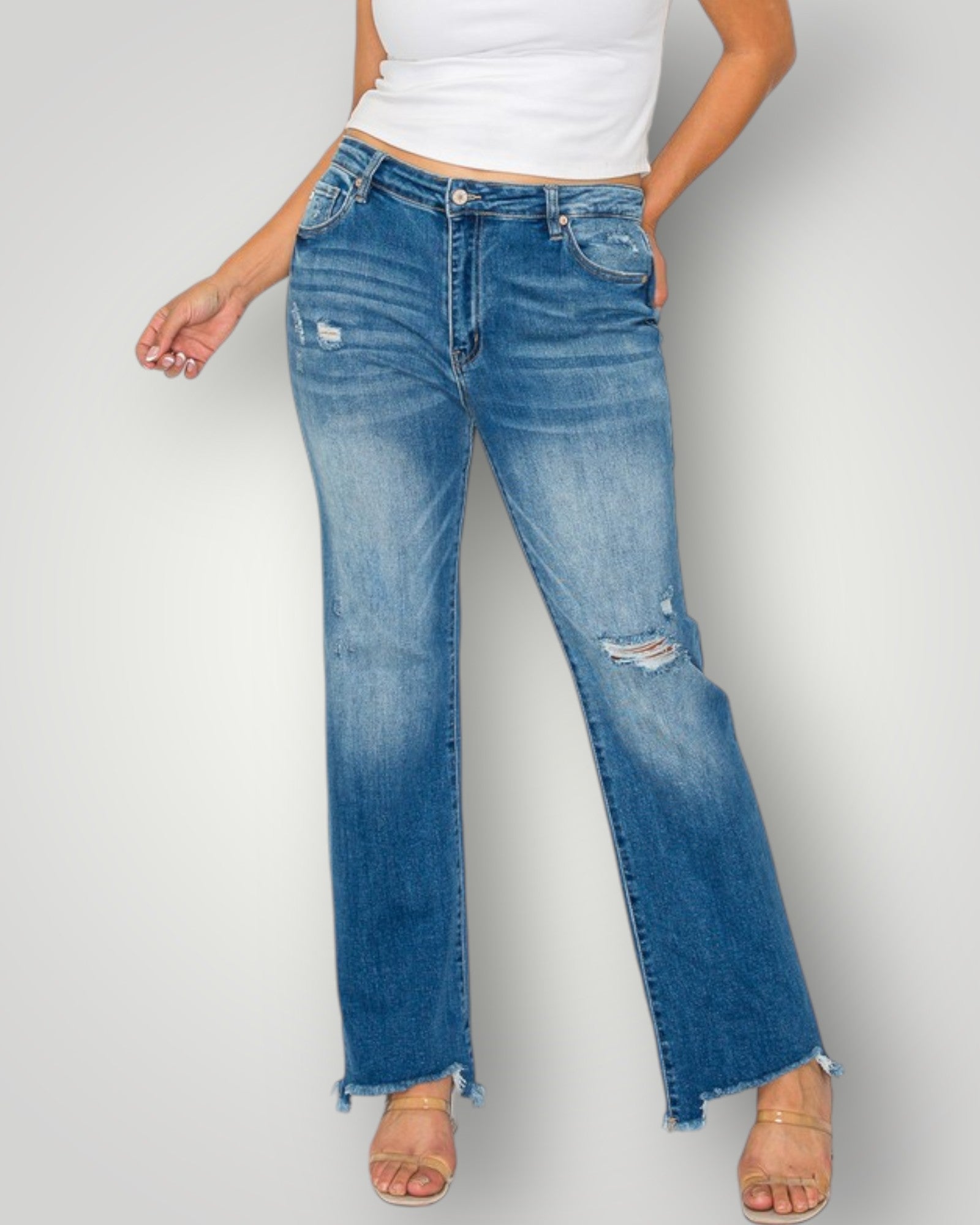 Person wearing blue jeans and a white top on a plain background