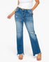 A model wearing a pair of medium-wash blue denim jeans with a distressed, ripped design on the thighs and knees, paired with a white tank top and beige sandals against a plain white background.