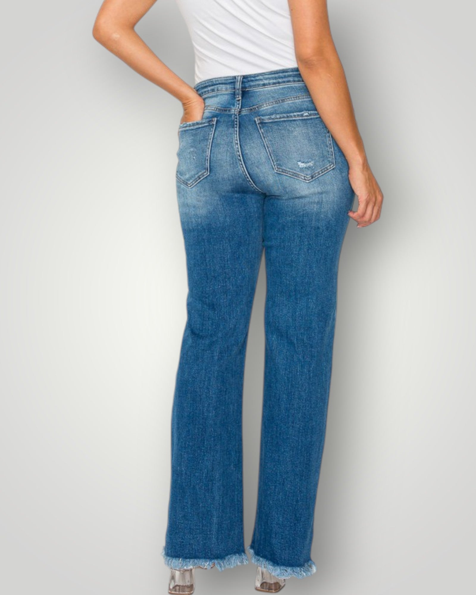 Blue jeans worn by a person on a plain background