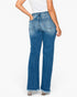 Rear view of a model wearing high-waisted, wide-leg blue denim jeans with a frayed hem, paired with a white top and metallic heels, against a plain white background.