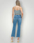 Woman wearing blue jeans and a gray crop top on a plain background