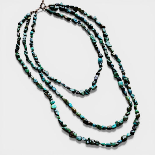 Long beaded necklace with green and black beads on a white background