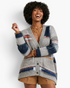 Beach Rose Co. model wearing a grey patchwork knit cardigan with striped patterns, V-neck, and front patch pockets.