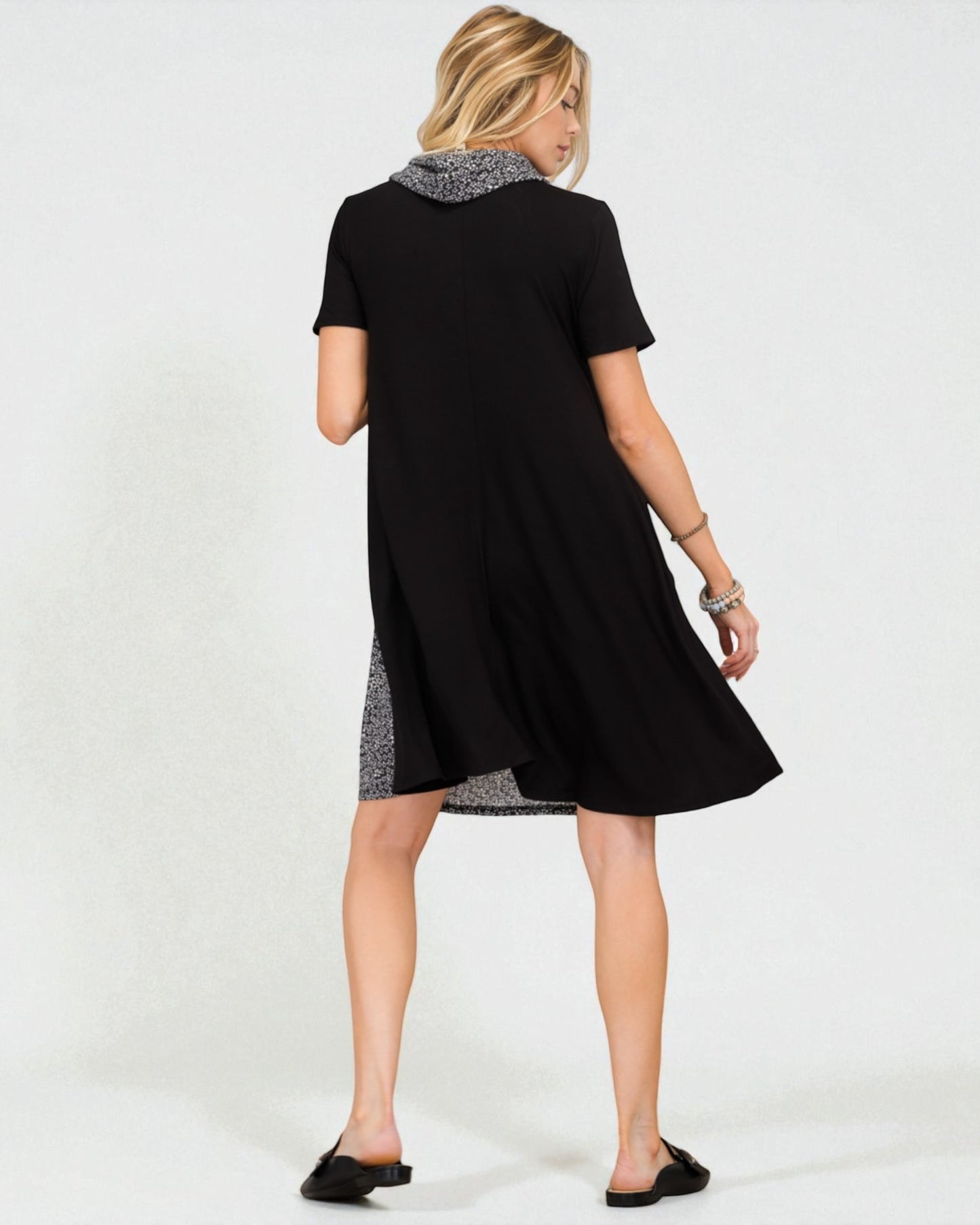 Woman wearing a black dress with a patterned hem on a white background