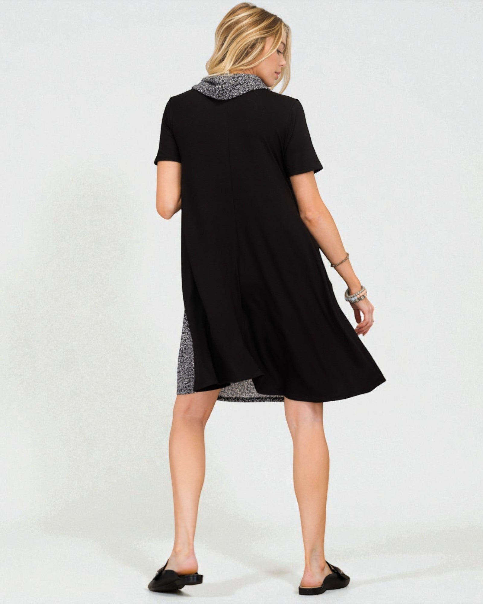 Woman wearing a black dress with a patterned hem on a white background