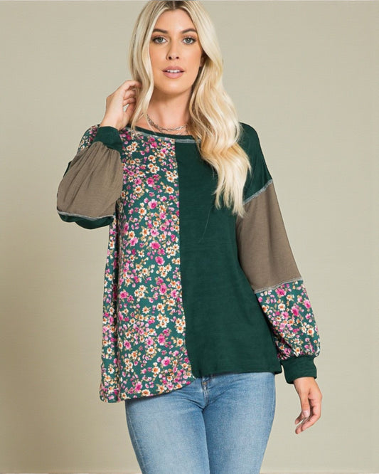 Woman wearing a floral and green long-sleeve top with a plain background