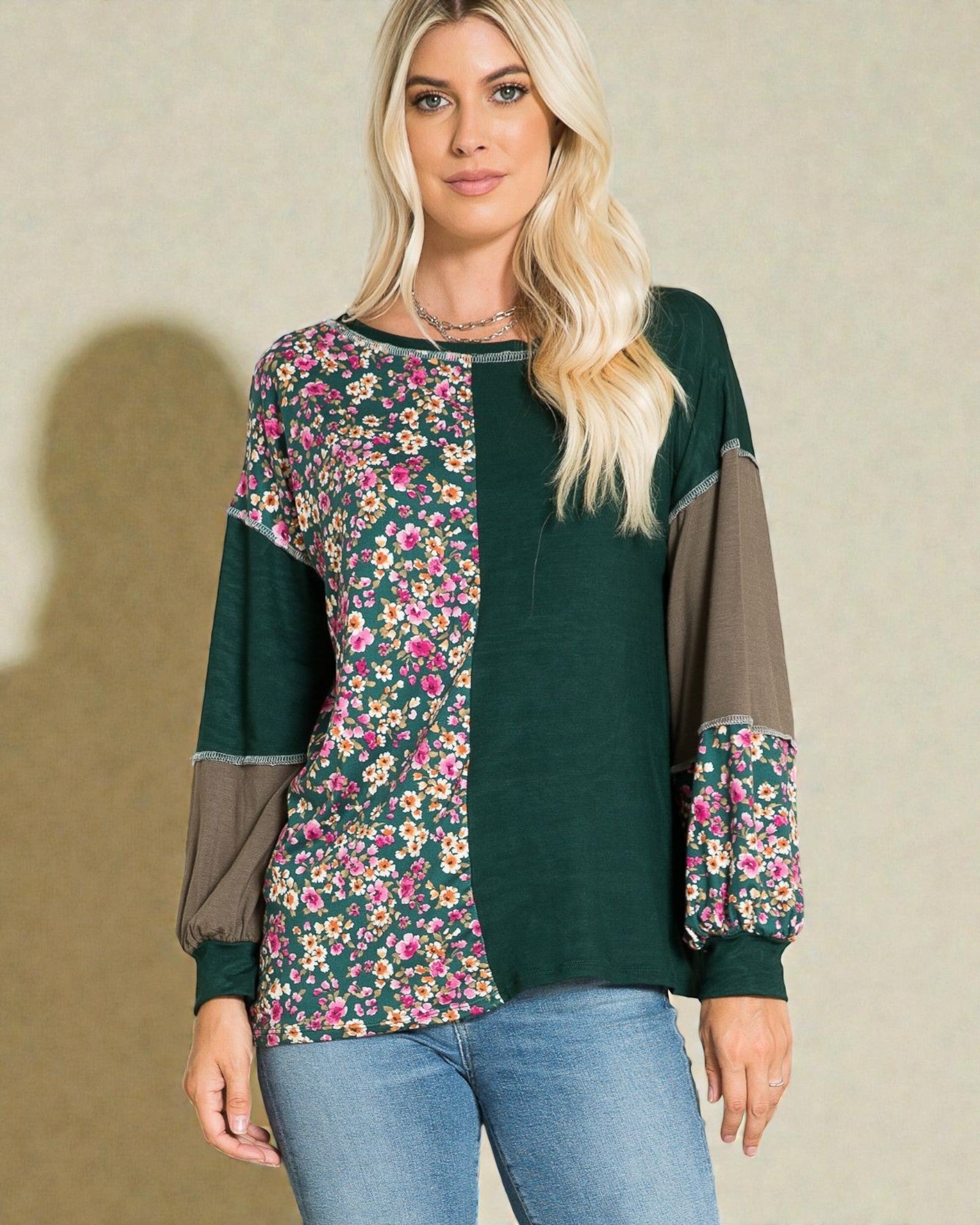 Woman wearing a green blouse with floral sleeves against a beige background