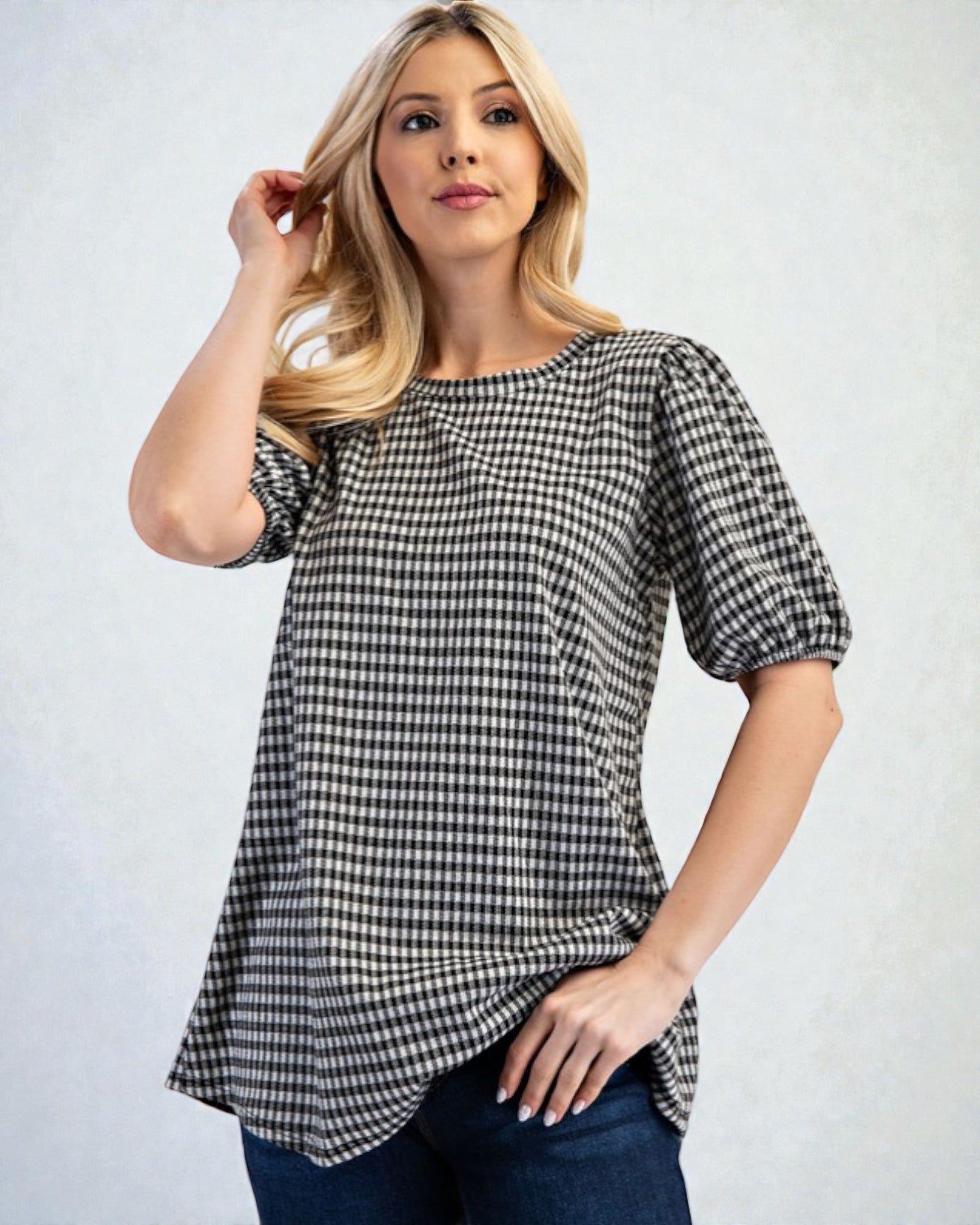 Woman wearing a black and white checkered blouse against a plain background