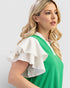 Woman wearing a green dress with a white blouse against a light background