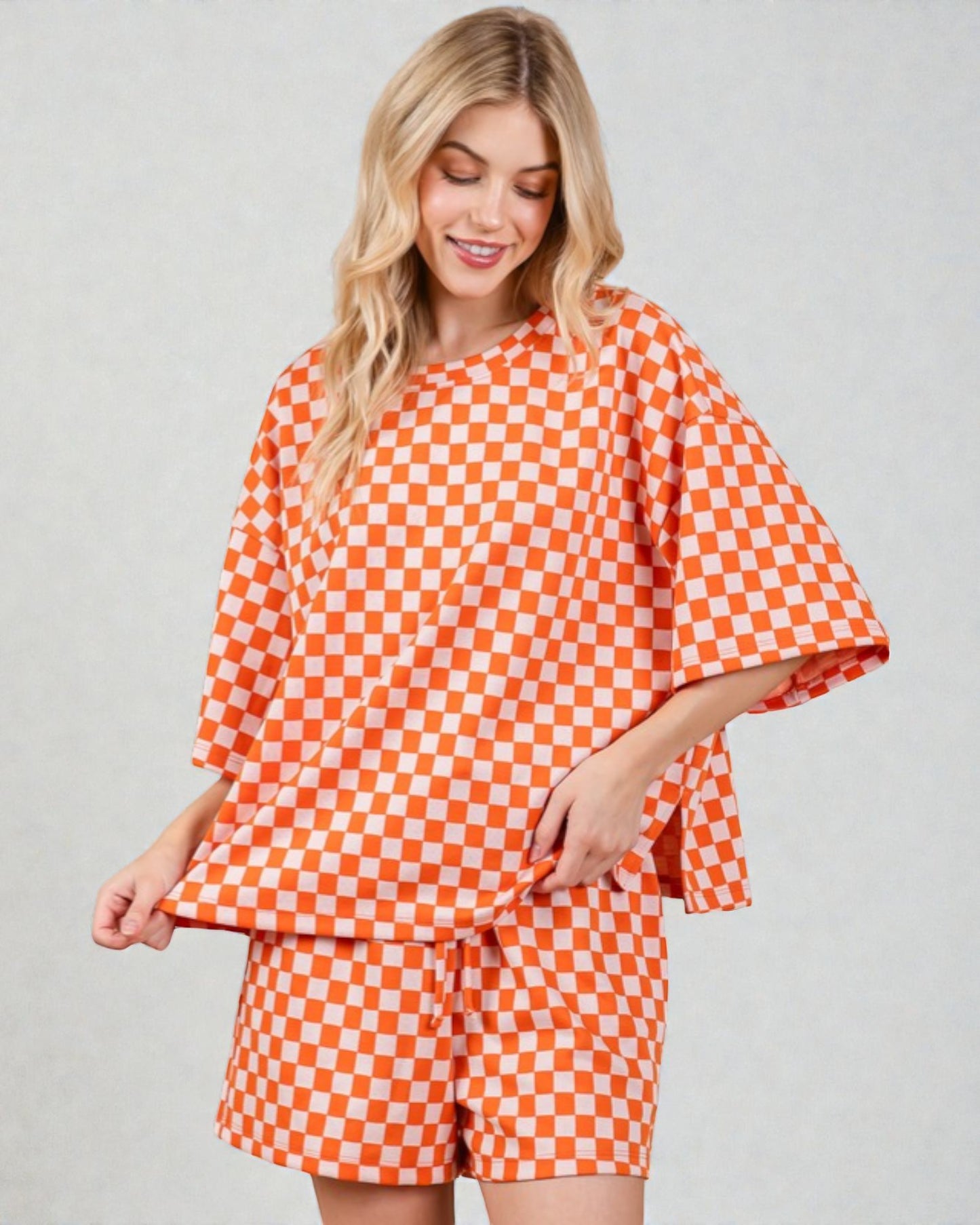 Woman wearing an orange and white checkered outfit on a plain background
