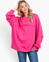 A woman modeling a bright pink oversized crewneck sweatshirt with long sleeves and a relaxed fit, paired with blue jeans against a plain white studio background.