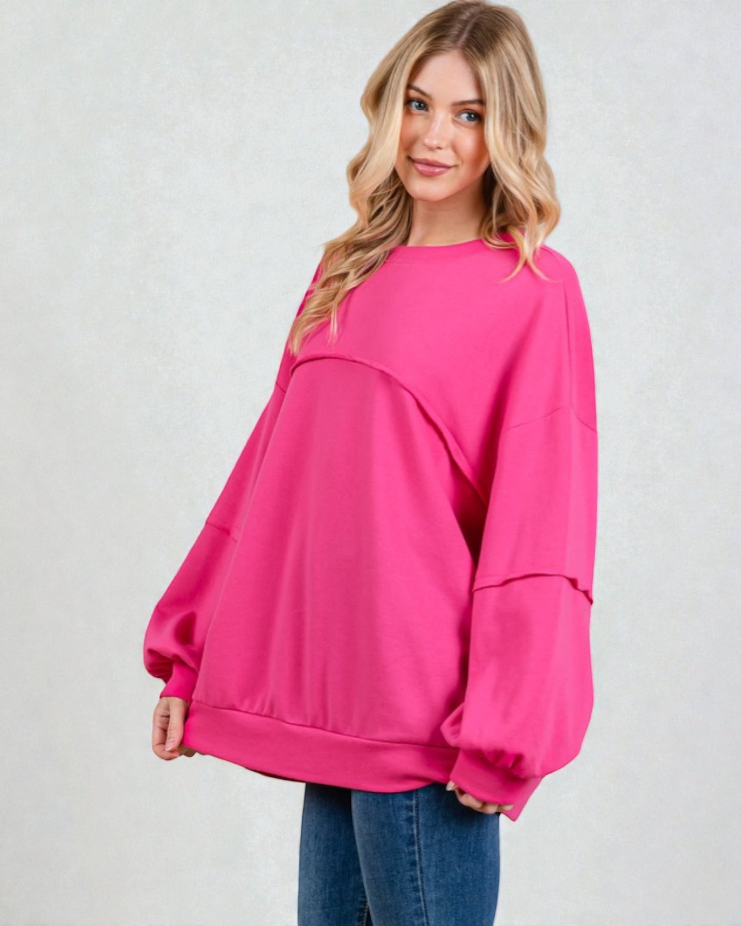 Woman wearing a bright pink oversized sweater on a white background