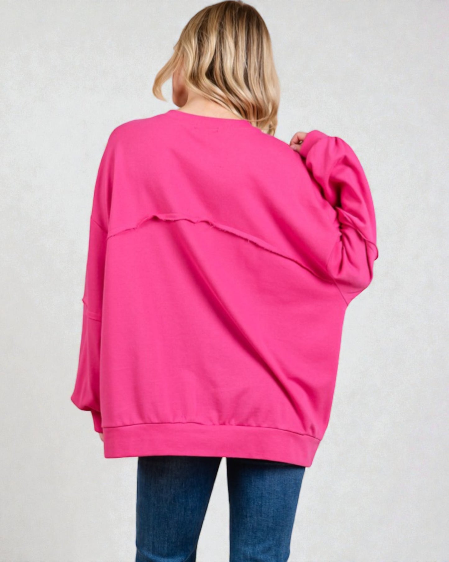 Person wearing a bright pink sweatshirt on a plain background