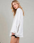 Woman wearing a white oversized shirt against a plain background