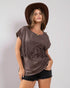 Woman wearing a brown fringe top and hat on a plain background