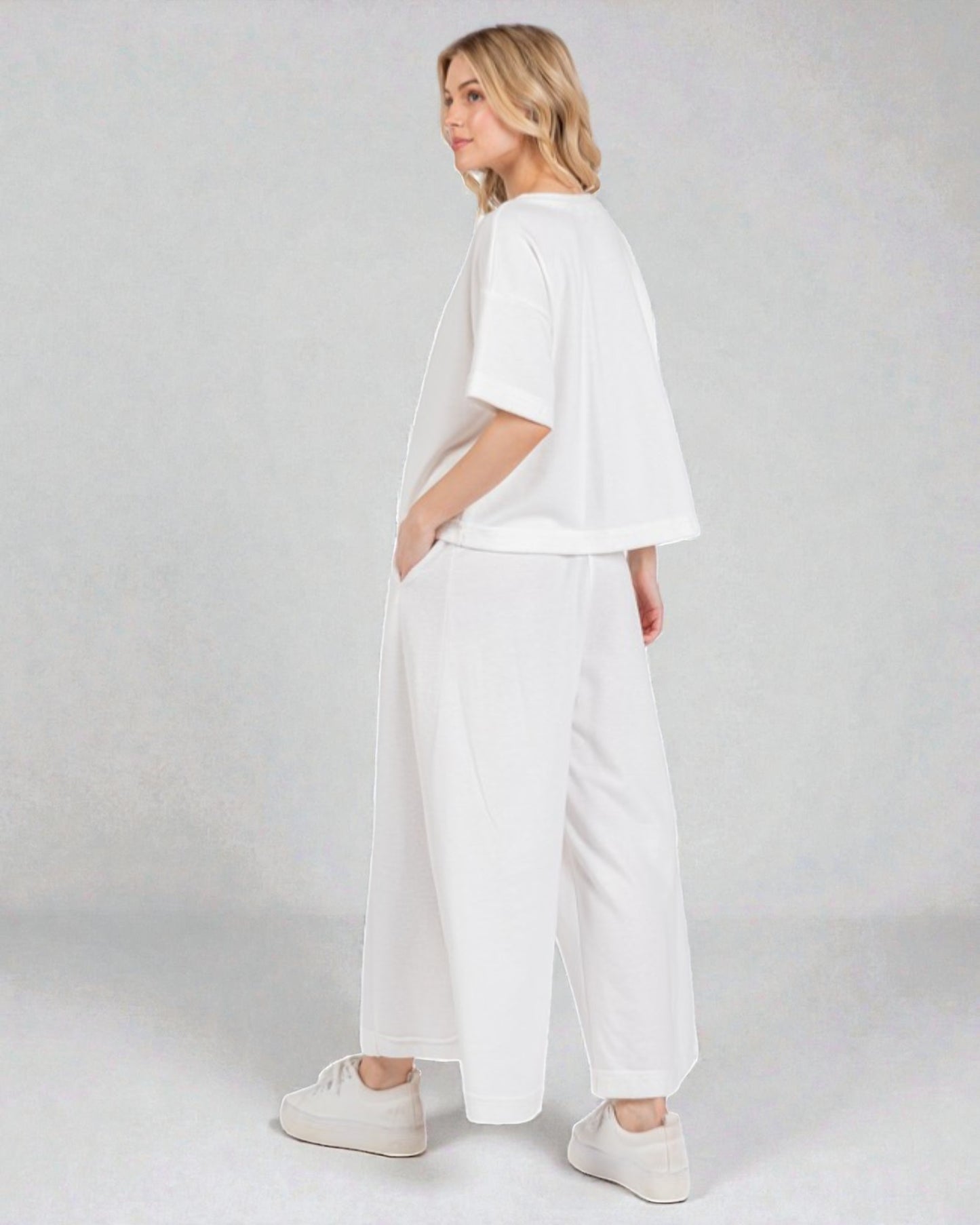 Woman wearing a white outfit on a plain background