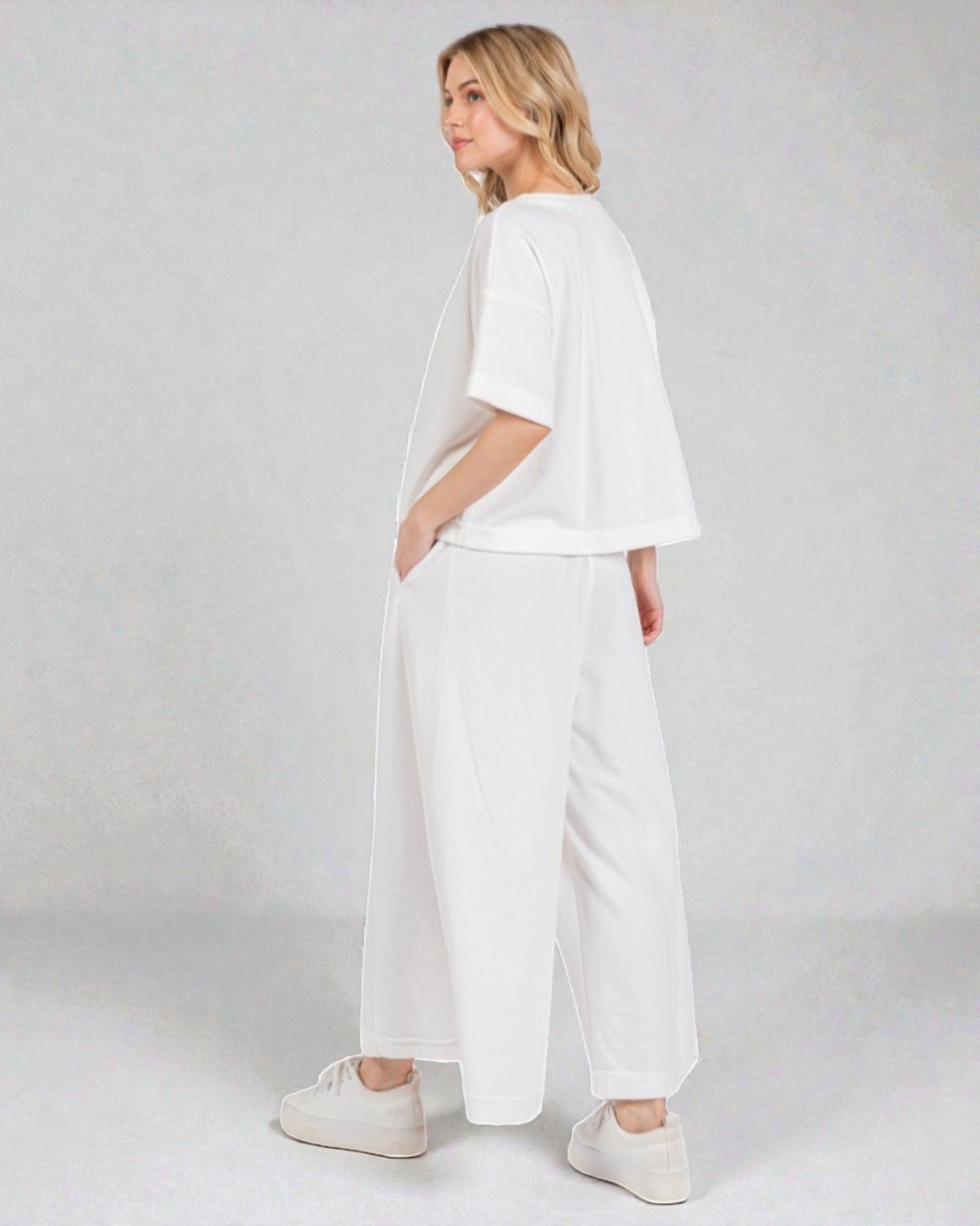 Woman wearing a white outfit on a plain background