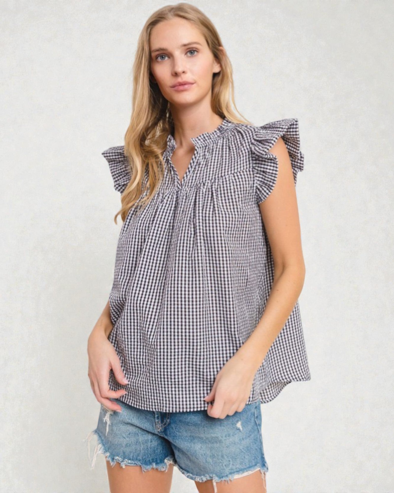Woman wearing a checkered top and denim shorts on a white background