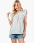 A woman modeling a light green and white gingham check top with ruffled cap sleeves and a smocked neckline, paired with denim shorts, against a plain white background.