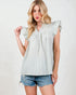 Woman wearing a light green checkered top and denim shorts on a white background