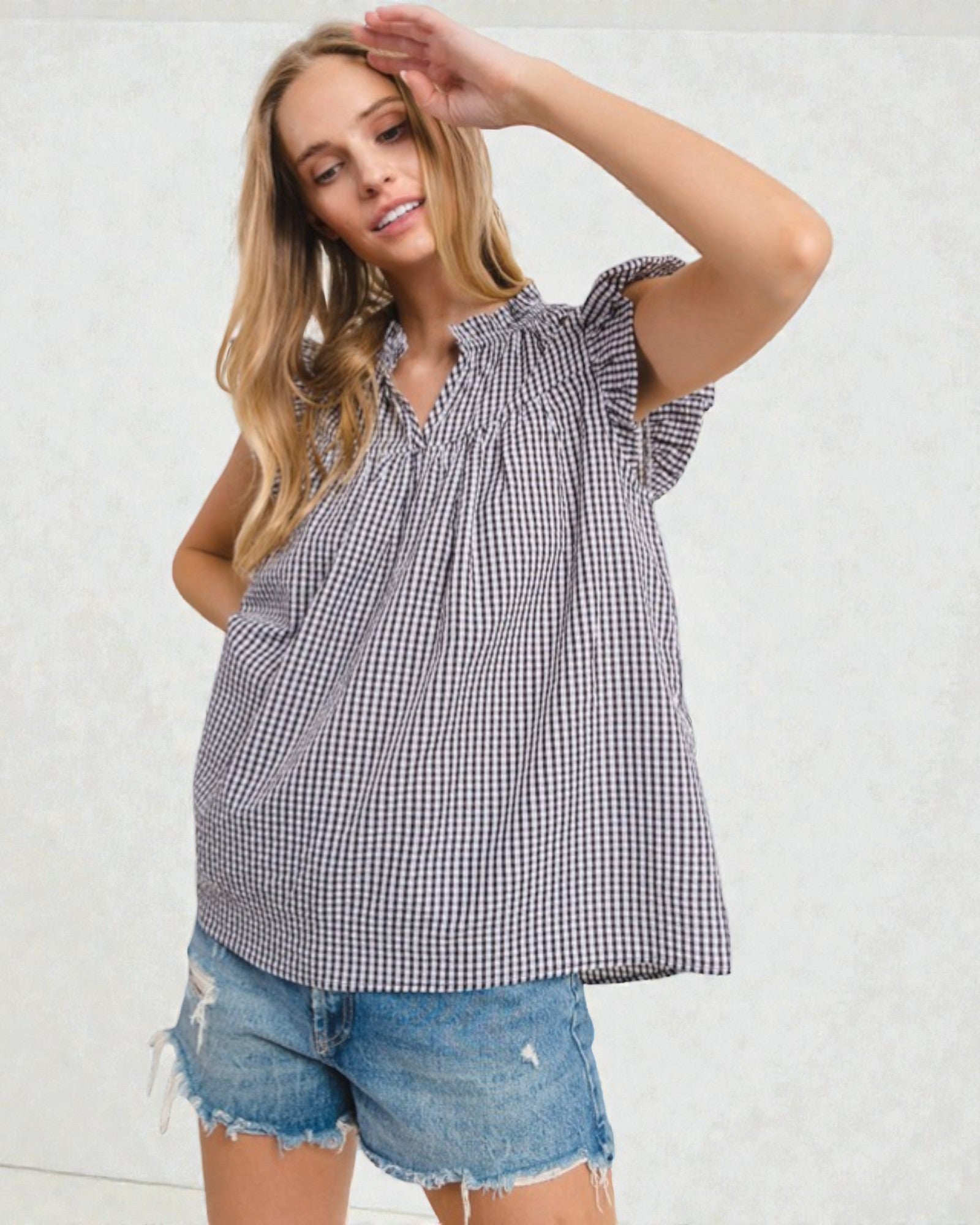 Woman wearing a checkered top and denim shorts against a white background