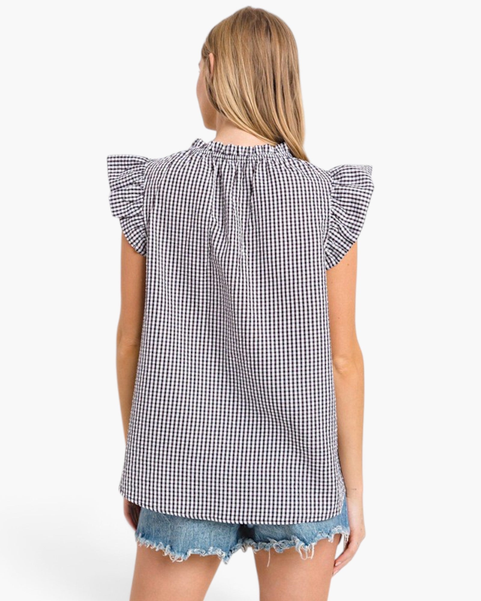 A woman shown from the back wearing a black and white gingham check top with ruffled cap sleeves and denim shorts against a plain white background.