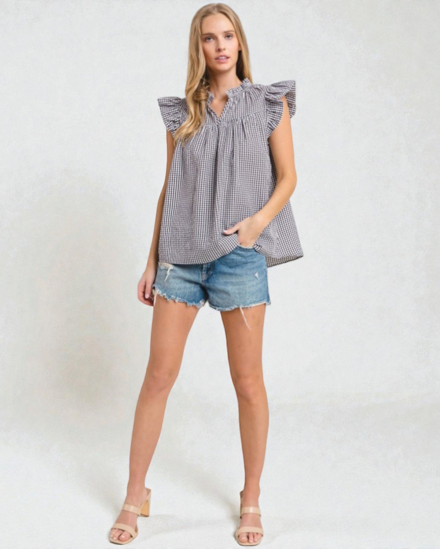 Woman wearing a checkered top and denim shorts on a white background