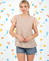 Woman wearing a beige top with floral sleeves and denim shorts against a colorful star pattern background