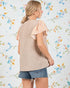 Woman wearing a beige knit top with floral sleeves against a floral-patterned background