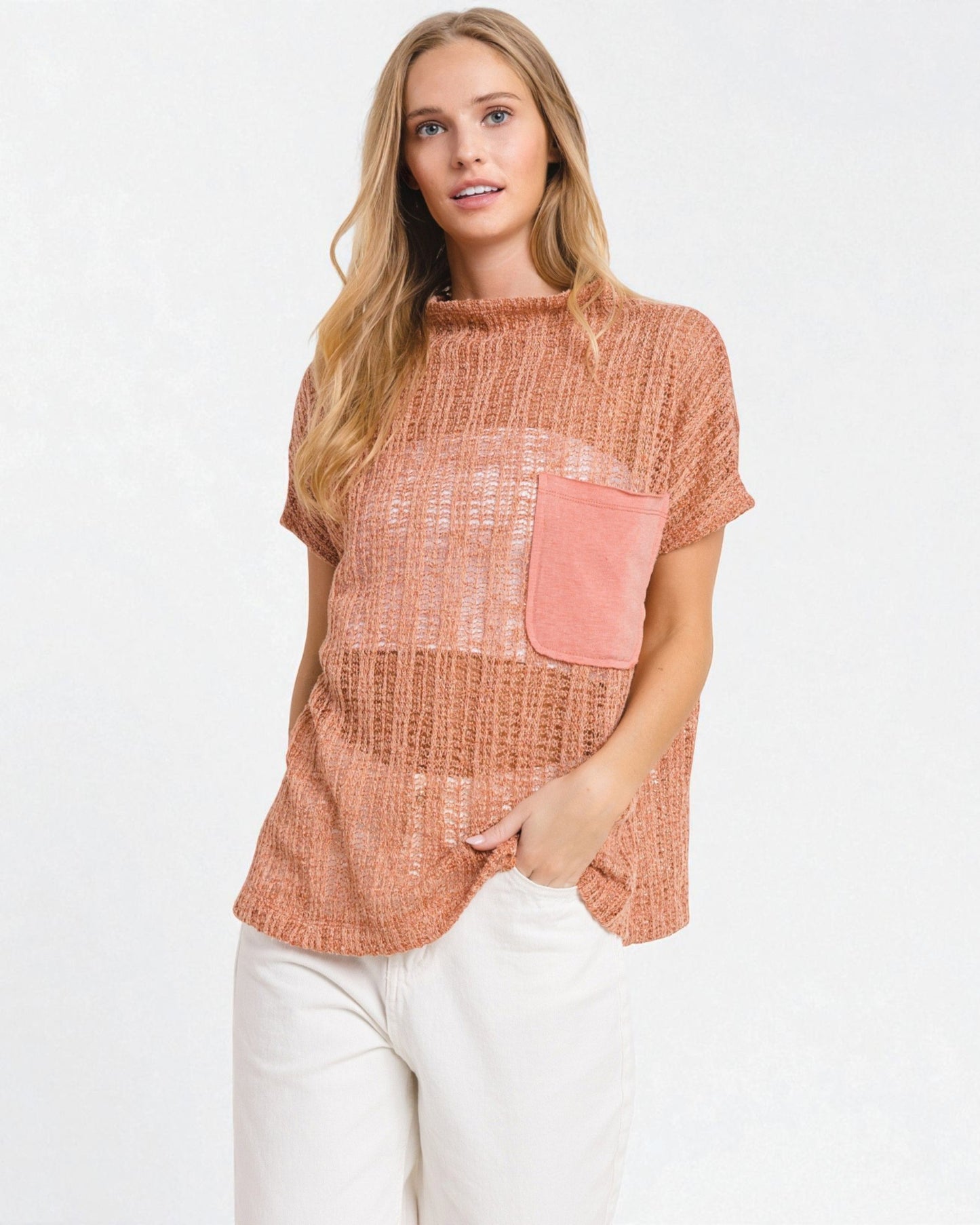 Woman wearing a rust-colored top with a pink pocket on a white background