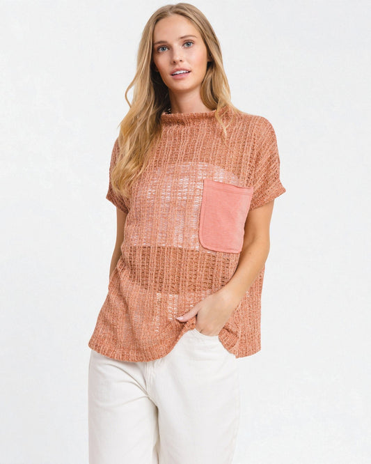 Woman wearing a rust-colored top with a pink pocket on a white background