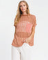 Woman wearing a rust-colored top with a pink pocket on a white background