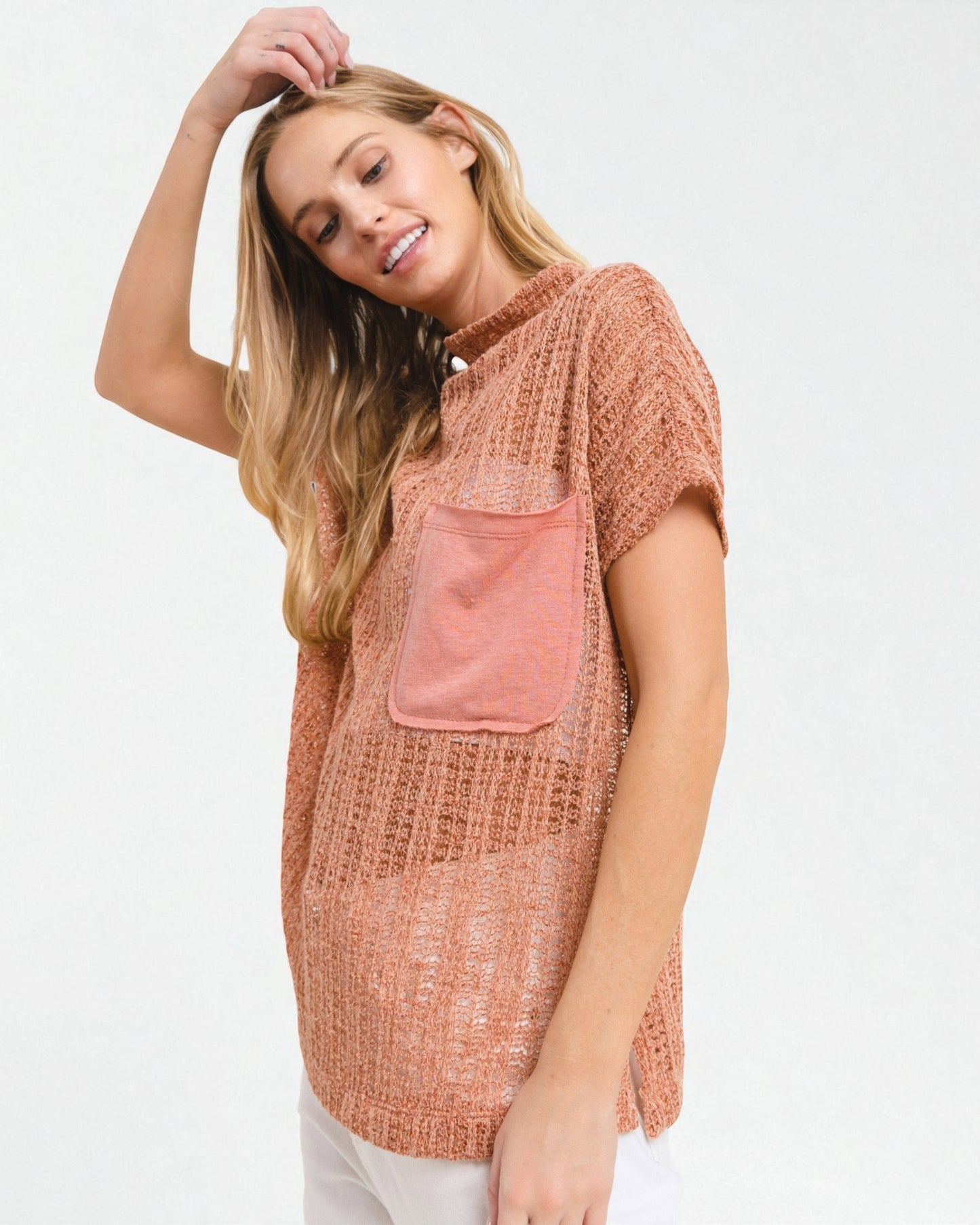 Woman wearing a brown textured top with a pink pocket on a white background