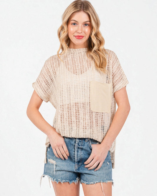 Woman wearing a beige knitted top and denim shorts on a white background