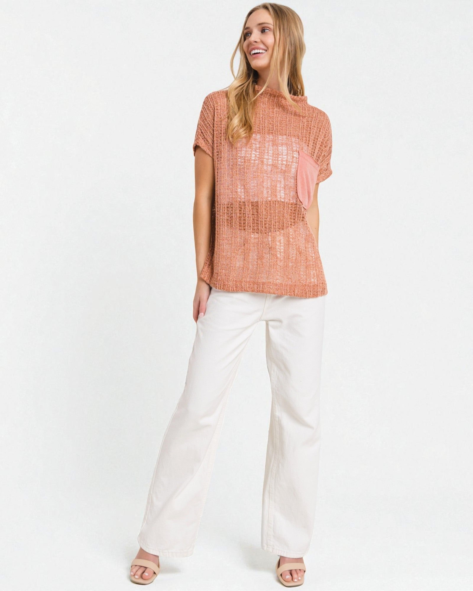 Woman wearing a rust-colored top and white pants on a white background