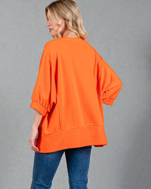 Person wearing an orange sweater and blue jeans on a gray background